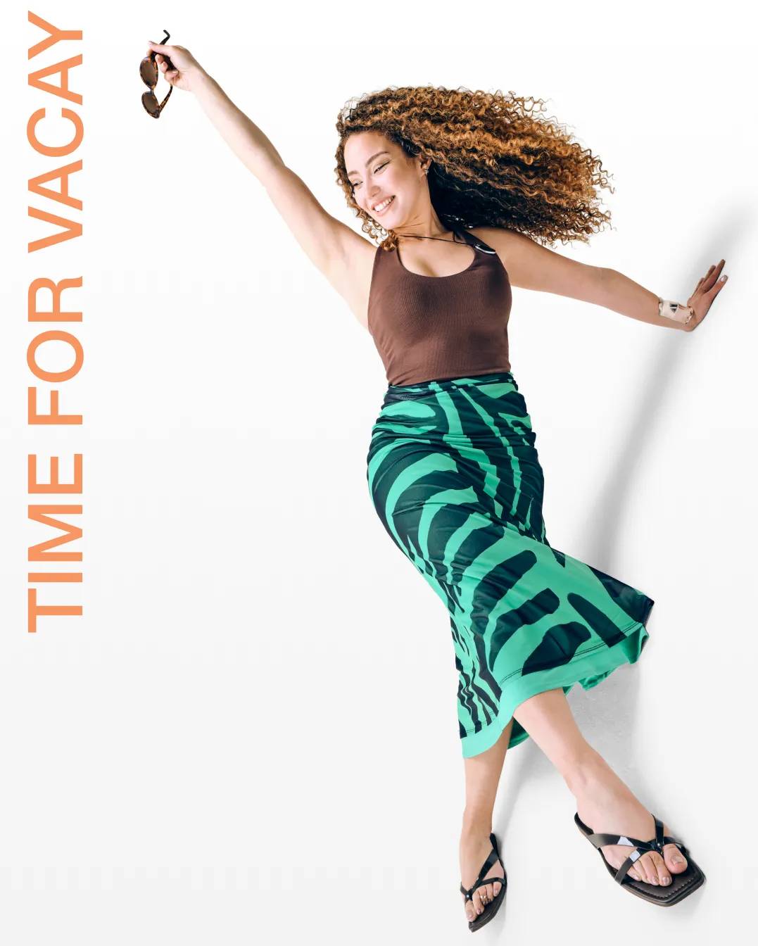 featuring a woman holding sunglasses, wearing black sandals.