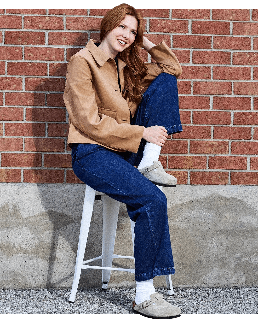 Woman against a brick wall wearing clogs