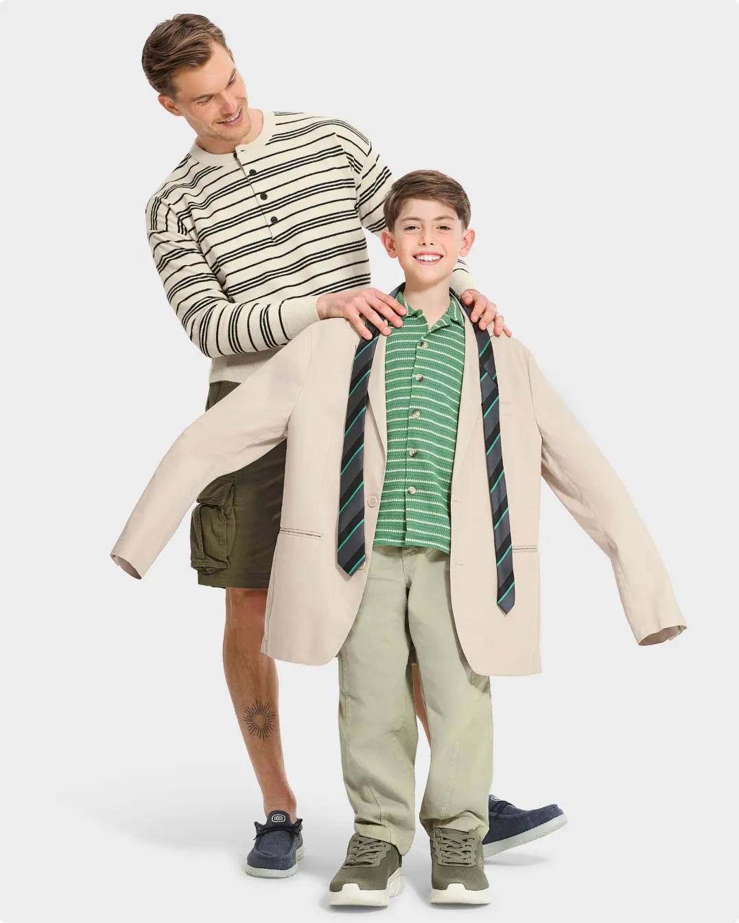A man putting an oversized suit jacket on a boy