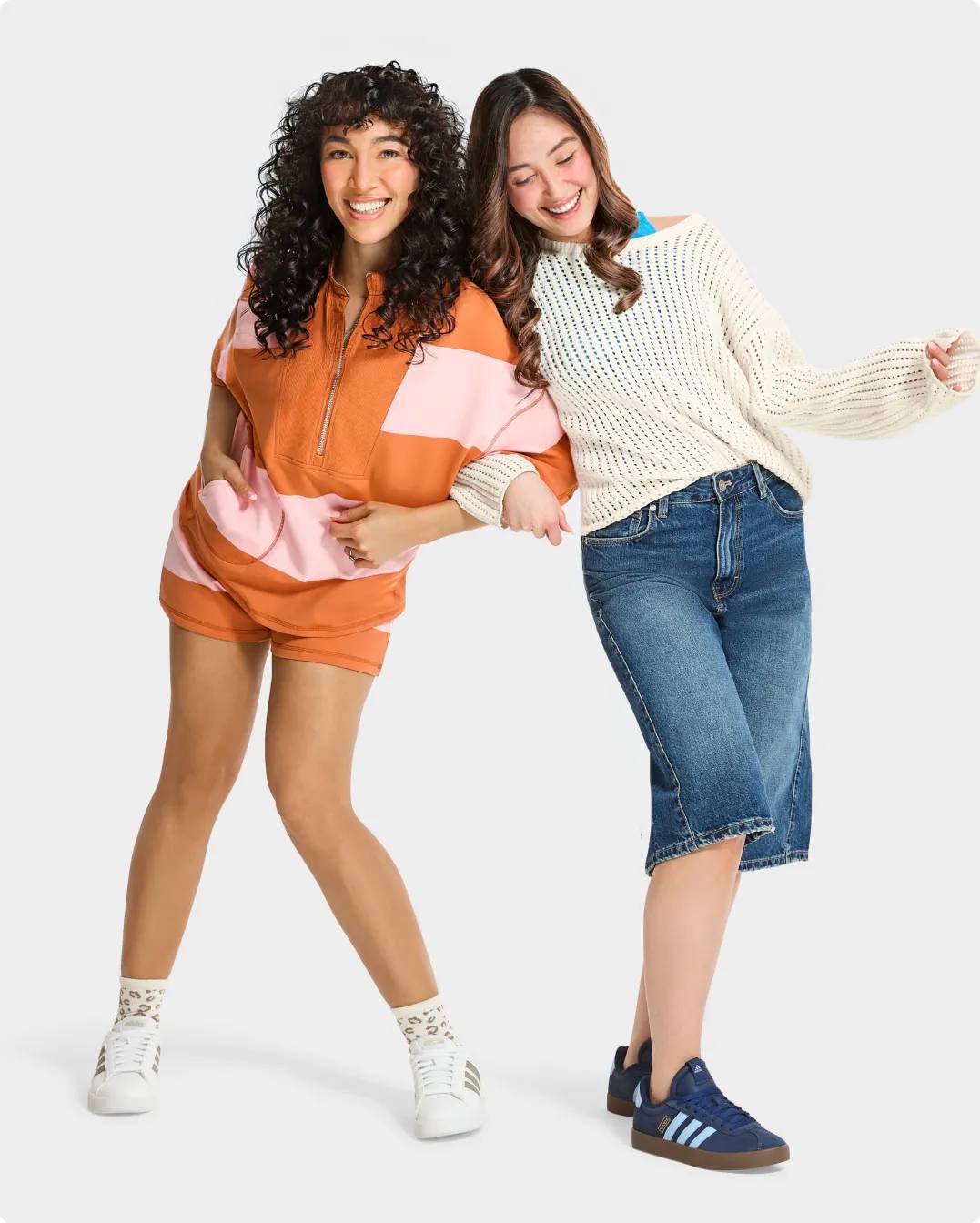 Two women wearing adidas sneakers linking arms