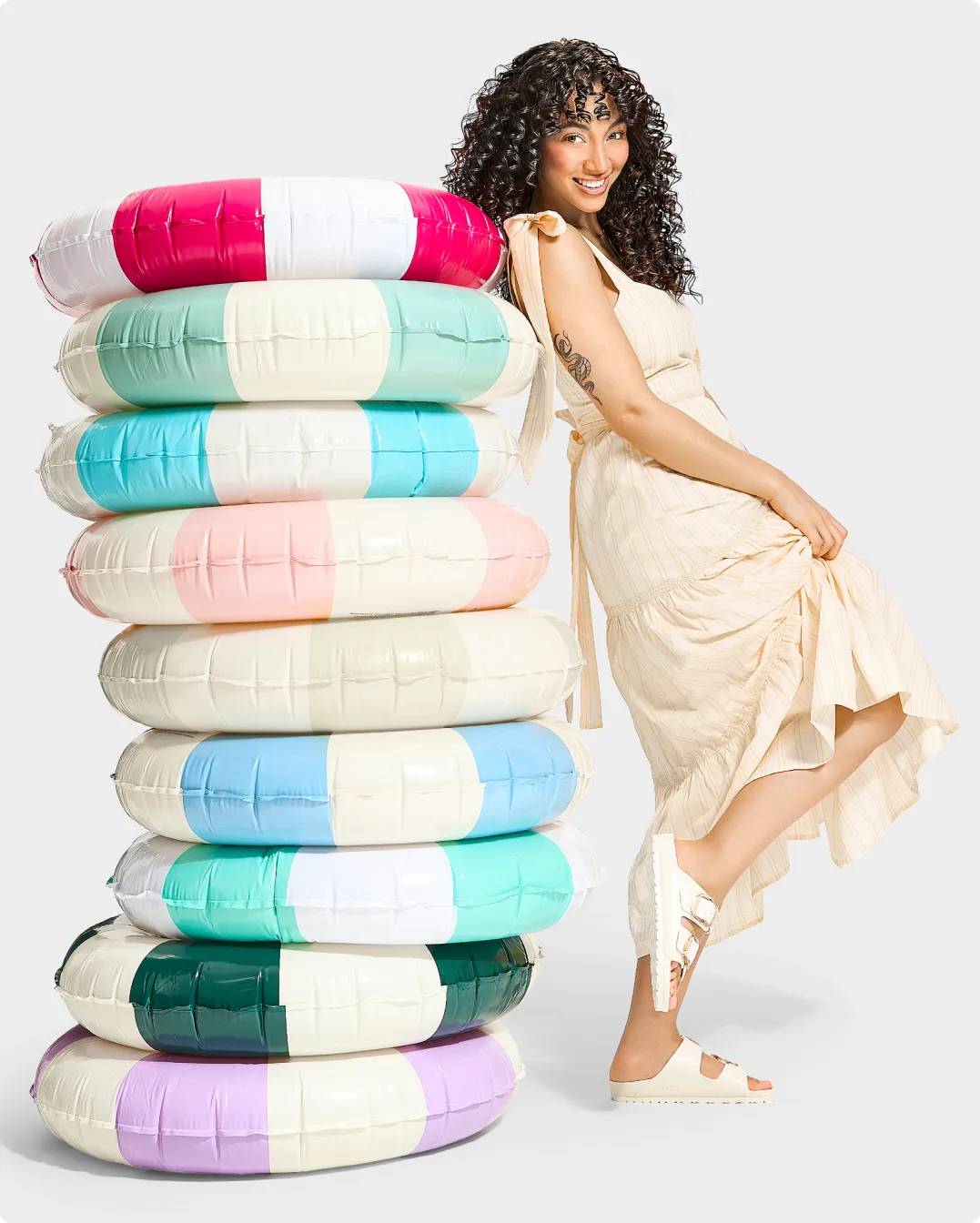 Woman wearing white Birkenstock EVA sandals leaning on a stack of floaties