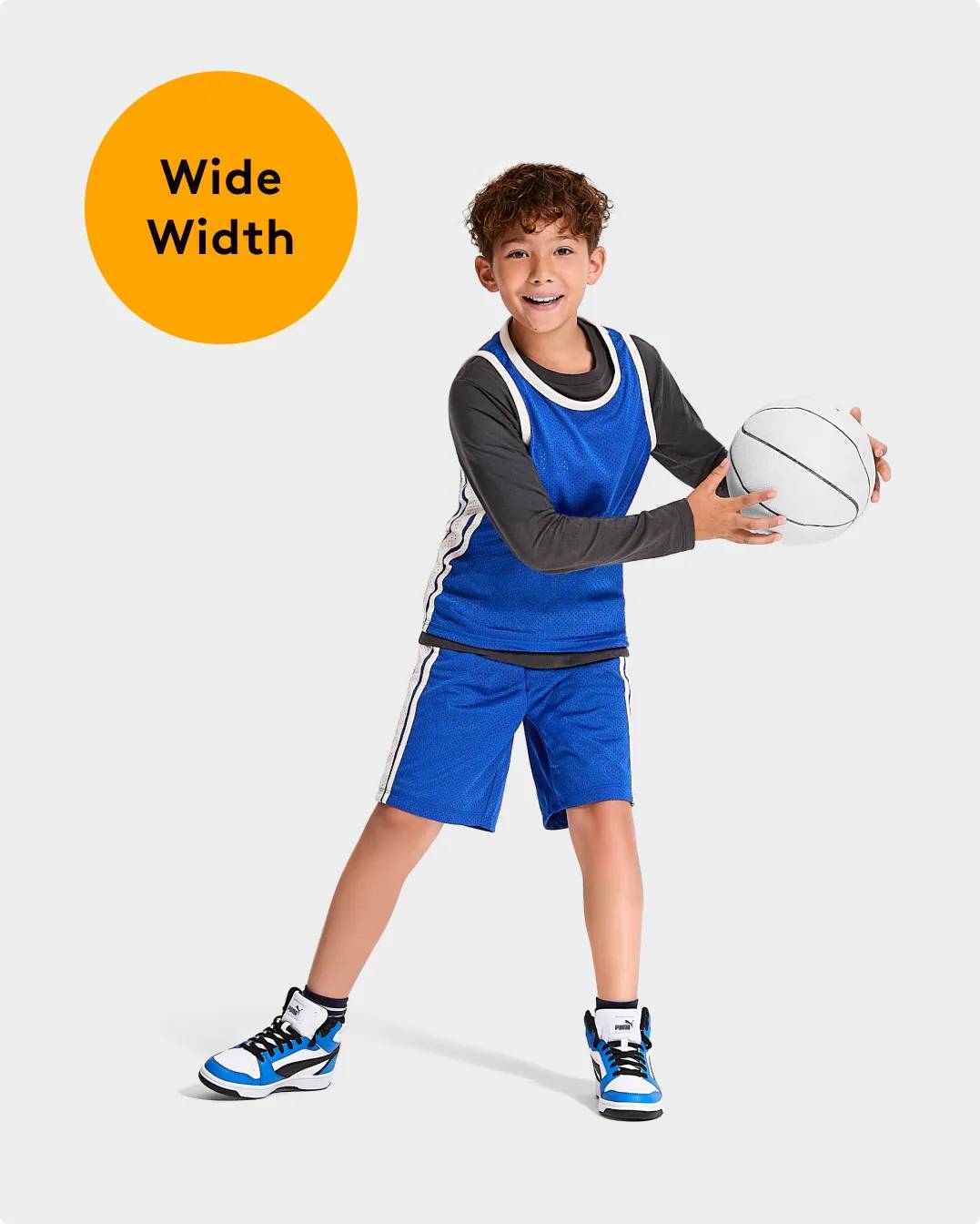 "Wide Width" Boy wearing PUMA basketball shoes holding a white basketball