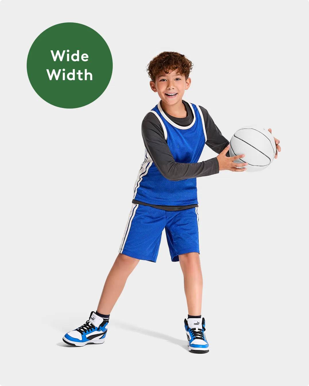 "Wide Width" Boy wearing PUMA basketball shoes holding a white basketball