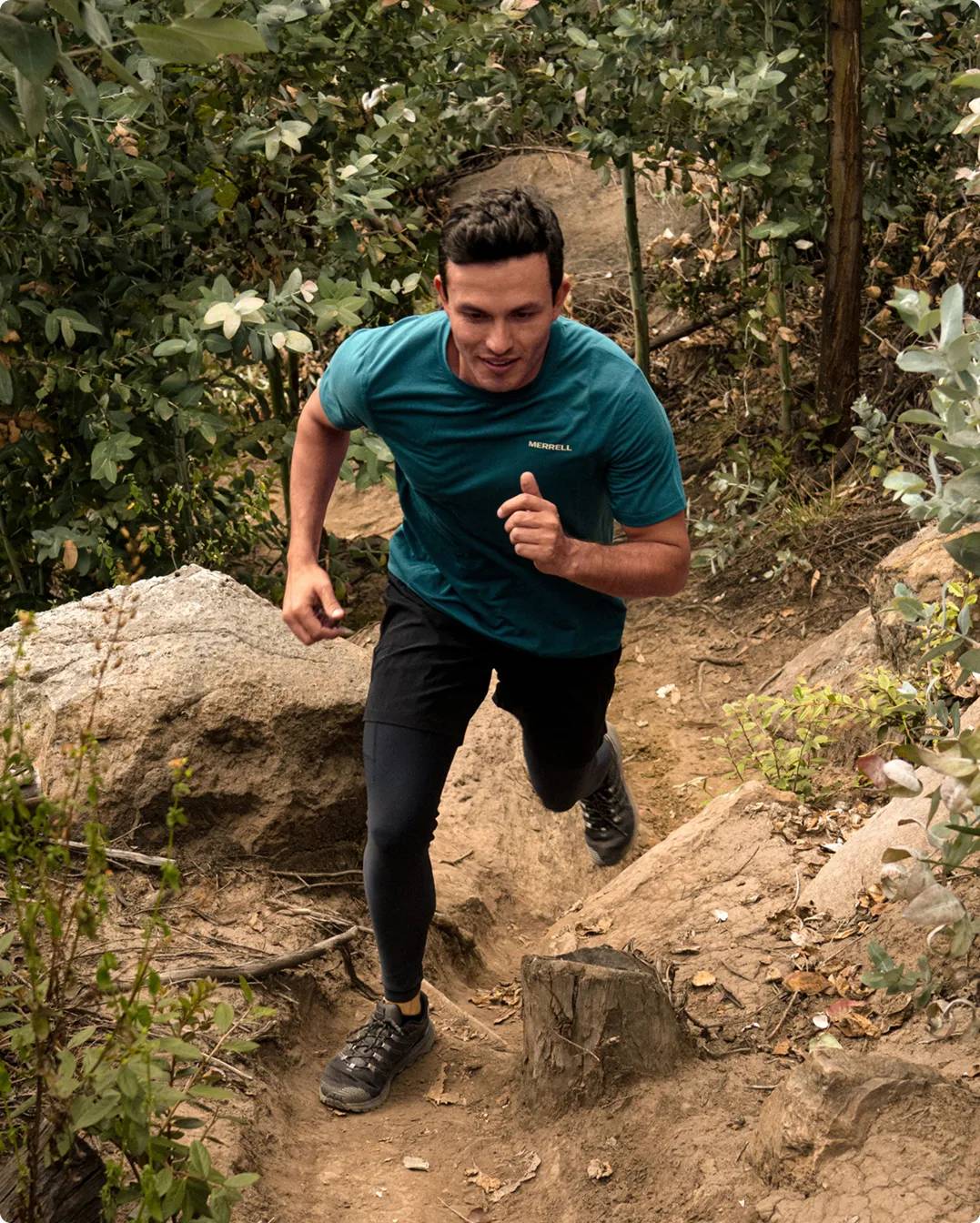 Man mid-stride on a hike in the forest wearing dark hiking shoes